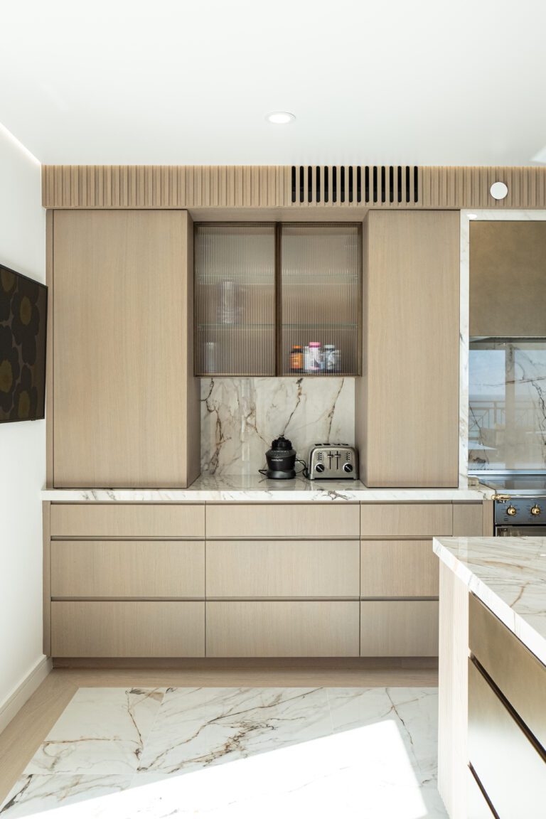 This design features a pocketed door on the top of the island, creating a dedicated coffee station. This aligns with one of the notable 2025 kitchen trends: incorporating functional cabinets directly onto island countertops