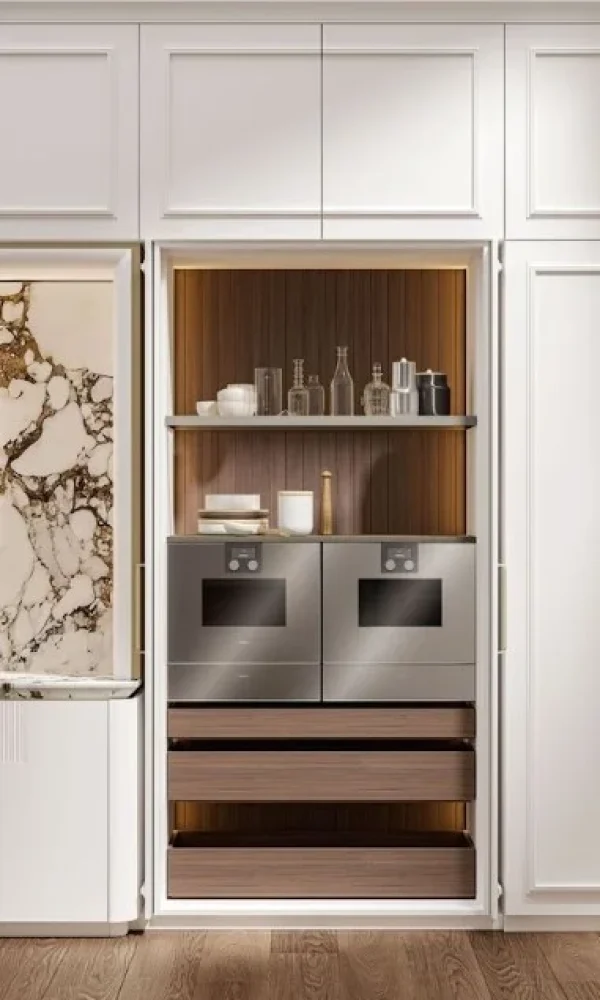Integrated wine bar and storage cabinet featuring a wine rack, glass holders, dark wood drawers, and a wine cooler, framed by white paneled cabinetry and two fluted glass display cabinets.